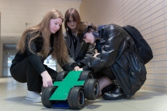 Trzy dziewczyny pochylające się nad pojazdem, konkurs-El-Robo-Mech_fot.Dariusz-Piekut_PB-31