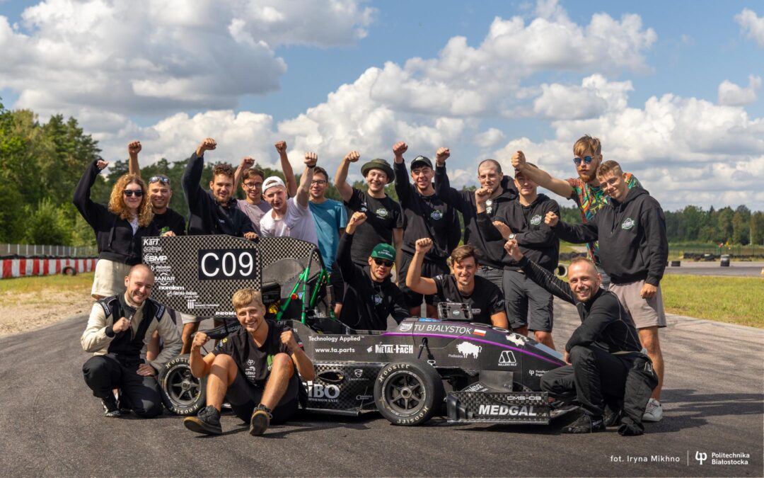 Grupa studentów skupiona wokół bolidu